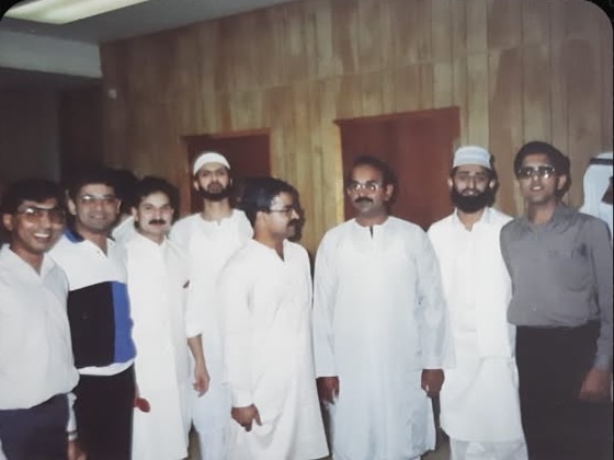 Eight founding members of PSA standing in a wood-panelled room, several in white shalwar kameez